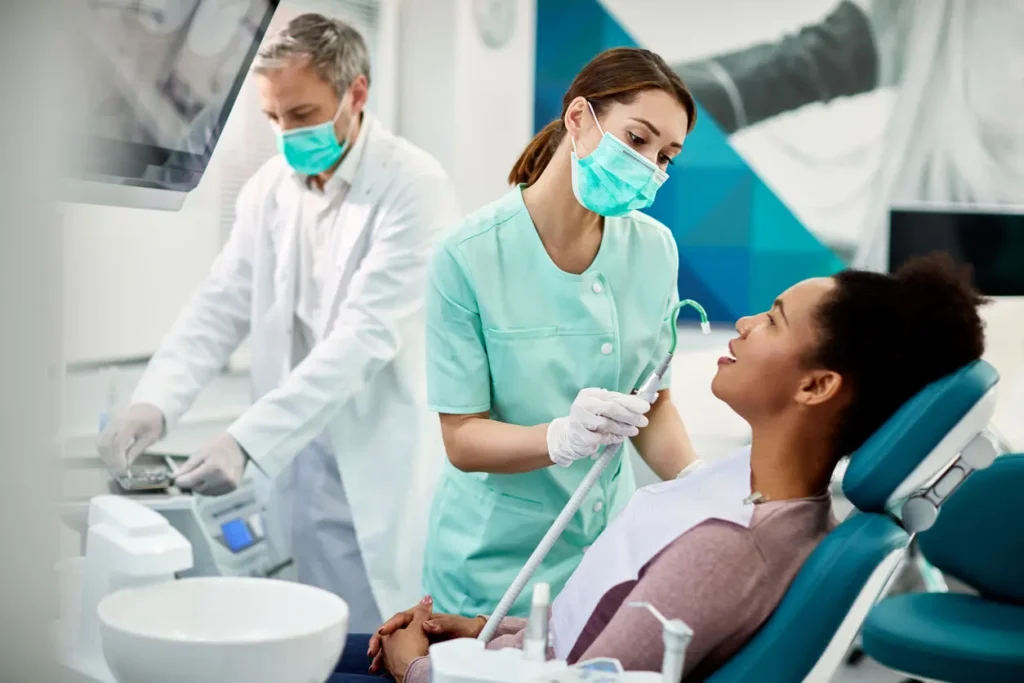 two dental assistants helping out female patient