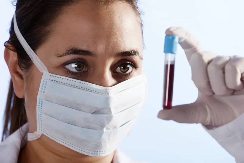 healthcare worker closely looking at blood sample